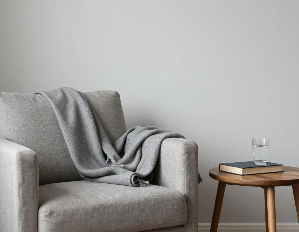 A quiet living room corner with an armchair and a side table in flat daylight